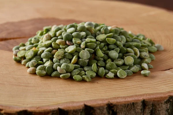 Stapel groene erwten op een houten log, close-up, top uitzicht, selectieve aandacht. — Stockfoto