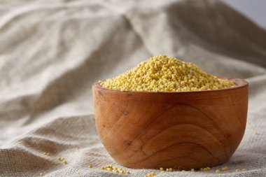 Darı saf masa örtüsü, yan görünüm, yakın çekim, seçici odak bir ahşap kase.