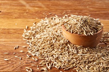 Yakın çekim Yulaf kabuğu çıkarılmış tane rustik ahşap arka plan, seçici odak üzerinde ahşap bir kasede heaped.