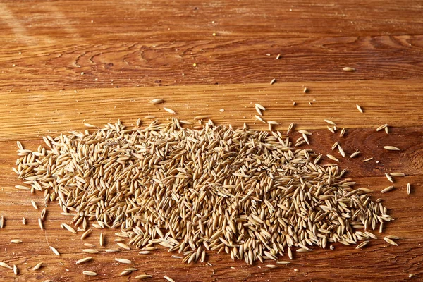 Ahşap arka plan, üstten görünüm, yakın çekim, makro, seçici odak soyulmamış yulaf taneleri yığını.