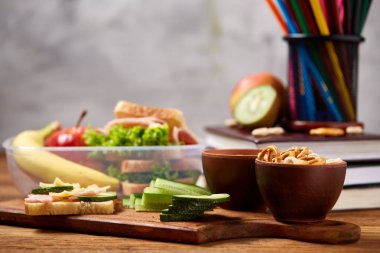 Okul veya sandviç ile öğle yemeği kutusu ve çeşitli renkli sebze ve meyve ahşap arka plan üzerinde piknik, yakın çekim.