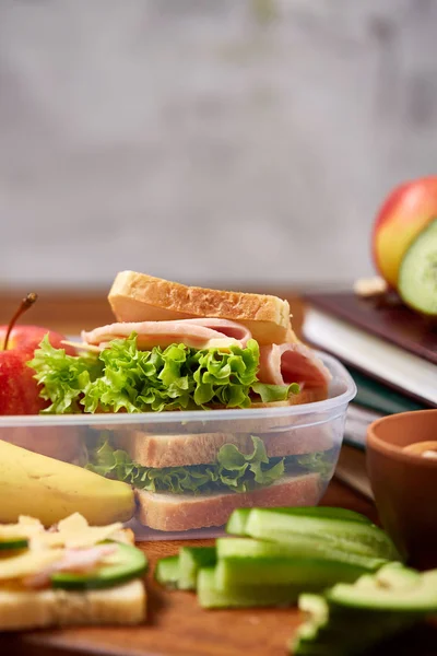 School of picknick doos van de lunch met broodje en diverse kleurrijke groenten en fruit op houten achtergrond, close-up. — Stockfoto