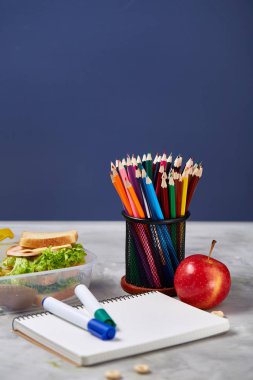 Geri okul kavramı, okul malzemeleri, bisküvi, paket öğle yemeği ve beslenme çantası beyaz yazı tahtası, seçici odak üzerinde.