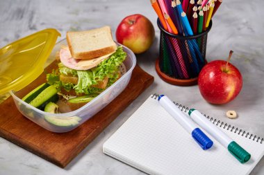 Geri okul kavramı, okul malzemeleri, bisküvi, paket öğle yemeği ve beslenme çantası beyaz yazı tahtası, seçici odak üzerinde.