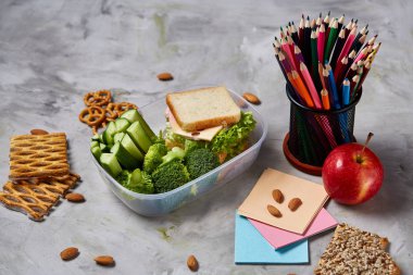 Geri okul kavramı, okul malzemeleri, bisküvi, paket öğle yemeği ve beslenme çantası beyaz yazı tahtası, seçici odak üzerinde.