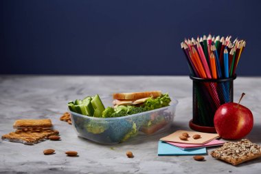 Geri okul kavramı, okul malzemeleri, bisküvi, paket öğle yemeği ve beslenme çantası beyaz yazı tahtası, seçici odak üzerinde.