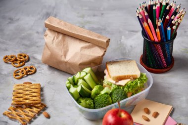 Geri okul kavramı, okul malzemeleri, bisküvi, paket öğle yemeği ve beslenme çantası beyaz yazı tahtası, seçici odak üzerinde.