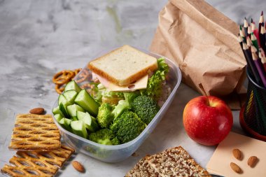 Geri okul kavramı, okul malzemeleri, bisküvi, paket öğle yemeği ve beslenme çantası beyaz yazı tahtası, seçici odak üzerinde.