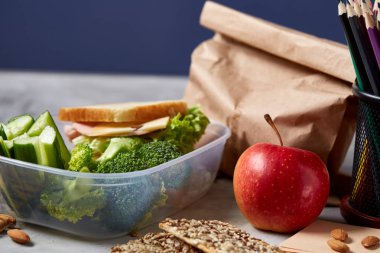 Geri okul kavramı, okul malzemeleri, bisküvi, paket öğle yemeği ve beslenme çantası beyaz yazı tahtası, seçici odak üzerinde.