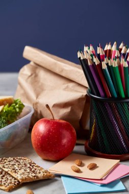 Geri okul kavramı, okul malzemeleri, bisküvi, paket öğle yemeği ve beslenme çantası beyaz yazı tahtası, seçici odak üzerinde.