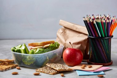 Geri okul kavramı, okul malzemeleri, bisküvi, paket öğle yemeği ve beslenme çantası beyaz yazı tahtası, seçici odak üzerinde.