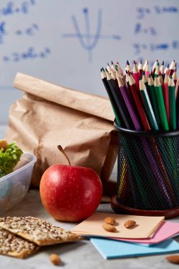 Geri okul kavramı, okul malzemeleri, bisküvi, paket öğle yemeği ve beslenme çantası beyaz yazı tahtası, seçici odak üzerinde.