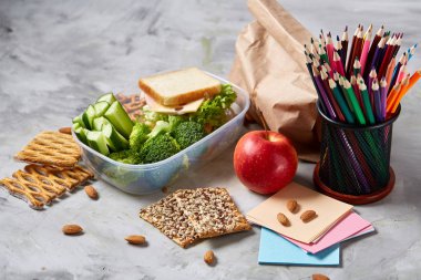 Geri okul kavramı, okul malzemeleri, bisküvi, paket öğle yemeği ve beslenme çantası beyaz yazı tahtası, seçici odak üzerinde.