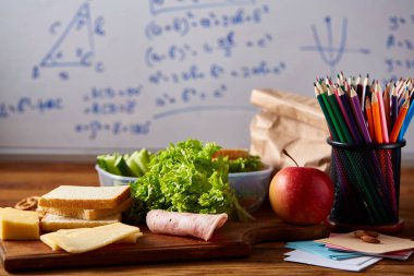 Geri okul kavramı, okul malzemeleri, bisküvi, paket öğle yemeği ve beslenme çantası beyaz yazı tahtası, seçici odak üzerinde.