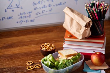 Geri okul kavramı, okul malzemeleri, bisküvi, paket öğle yemeği ve beslenme çantası beyaz yazı tahtası, seçici odak üzerinde.