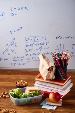 Geri okul kavramı, okul malzemeleri, bisküvi, paket öğle yemeği ve beslenme çantası beyaz yazı tahtası, seçici odak üzerinde.