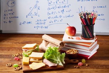 Geri okul kavramı, okul malzemeleri, bisküvi, paket öğle yemeği ve beslenme çantası beyaz yazı tahtası, seçici odak üzerinde.