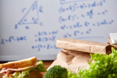 Geri okul kavramı, okul malzemeleri, bisküvi, paket öğle yemeği ve beslenme çantası beyaz yazı tahtası, seçici odak üzerinde.