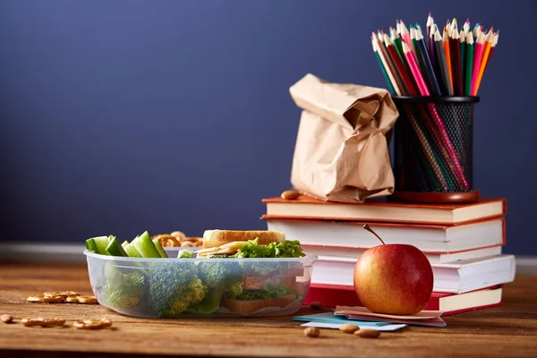 Back to School concept, school supplies, biscuits and lunchbox on wooden desk, selective focus, close-up. — Stock Photo, Image