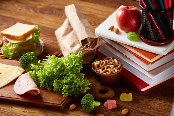 Concetto di pausa pranzo scolastica con pranzo sano e materiale scolastico su scrivania in legno, focus selettivo . — Foto Stock