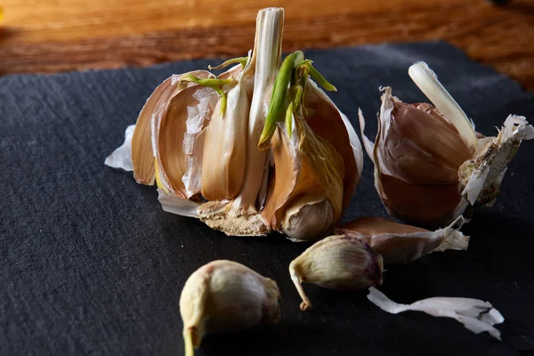 Knoblauchteile in Nahaufnahme auf dunkelschwarzem Hintergrund, geringe Schärfentiefe, selektiver Fokus, Makro — Stockfoto