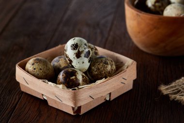 Bıldırcın yumurtası kova, kutu ve ıslak zeminde ahşap arka plan, seçici odak keten bir peçete ile rustik natürmort