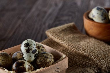 Bıldırcın yumurtası kova, kutu ve ıslak zeminde ahşap arka plan, seçici odak keten bir peçete ile rustik natürmort