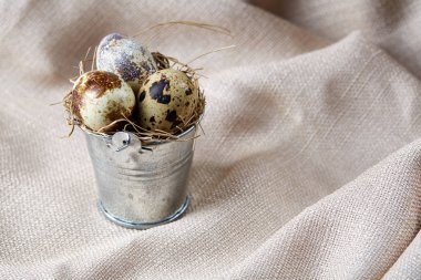 Bıldırcın yumurtası dekoratif bir kova ve bazı yumurta bir saf masa örtüsü, üstten görünüm, yakın çekim