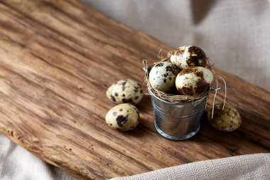 Küçük dekoratif kova dolu Bıldırcın yumurta koyu ahşap masa, yakın çekim, seçici odak ile.
