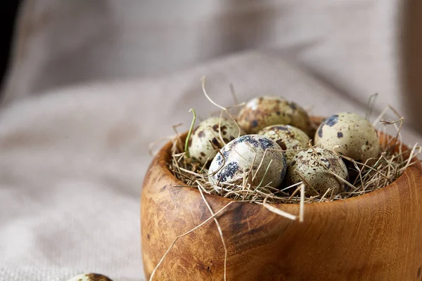 Huevos de codorniz en un tazón de madera en un mantel hecho en casa, vista superior, primer plano — Foto de Stock