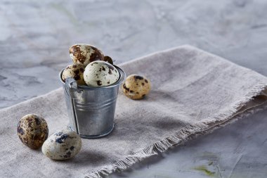 Küçük dekoratif kova peçete bıldırcın yumurtalarının dolu beyaz dokulu arka plan, yakın çekim, seçici odak üzerinde.