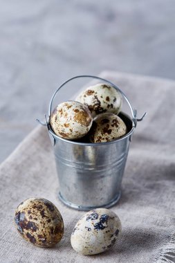 Küçük dekoratif kova peçete bıldırcın yumurtalarının dolu beyaz dokulu arka plan, yakın çekim, seçici odak üzerinde.