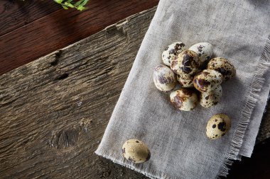 Piramit peçeteye Şimşir dalları ile düzenlenmiş bir ahşap masa, yakın çekim, seçici odak üzerinde bıldırcın yumurtası.