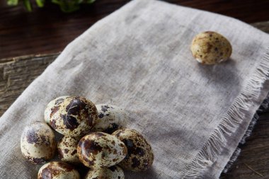 Piramit peçeteye Şimşir dalları ile düzenlenmiş bir ahşap masa, yakın çekim, seçici odak üzerinde bıldırcın yumurtası.