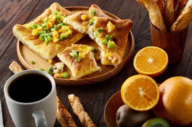 Sabah bir fincan kahve, breadsticks, meyve pasta ve ahşap zemin üzerine portakal konseptiyle.