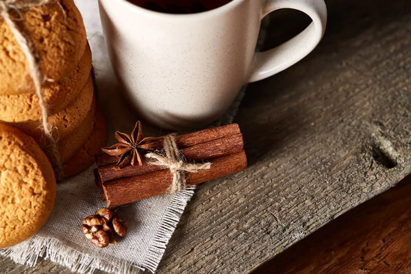 Traditional Christmas tea concept with a cup of hot tea, cookies and decorations on a wooden table, selective focus