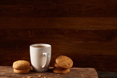 Ahşap ahşap arka plan, üstten görünüm, seçici odak parçası üzerinde çay ve tatlı kurabiye beyaz porselen kupa