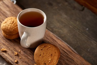 Ahşap ahşap arka plan, üstten görünüm, seçici odak parçası üzerinde çay ve tatlı kurabiye beyaz porselen kupa