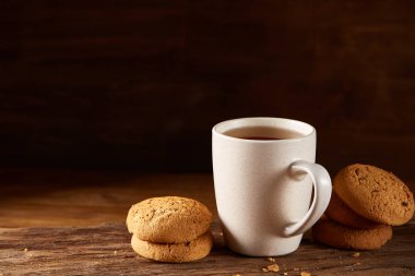 Ahşap ahşap arka plan, üstten görünüm, seçici odak parçası üzerinde çay ve tatlı kurabiye beyaz porselen kupa