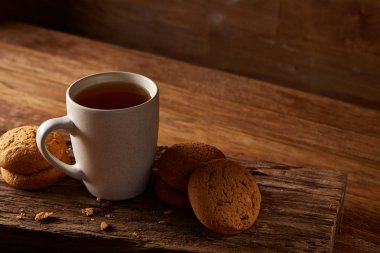 Ahşap ahşap arka plan, üstten görünüm, seçici odak parçası üzerinde çay ve tatlı kurabiye beyaz porselen kupa