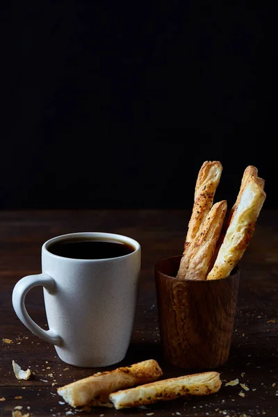 Tasse à café et bâtonnets de pain sur un vieux fond en bois, gros plan, mise au point sélective . — Photo