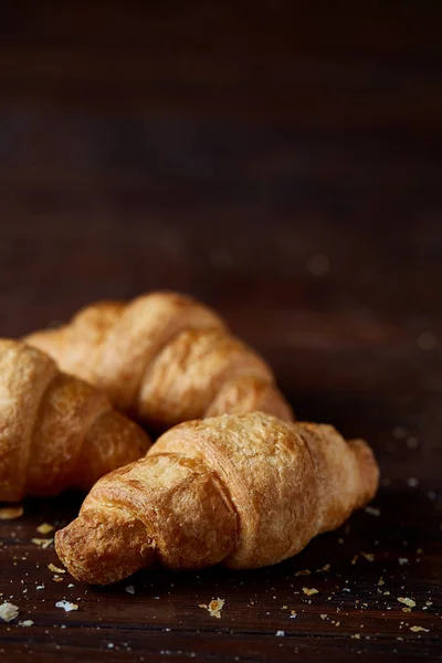 Tasty buttery croissants on an old wooden table, close-up, selective focus, shallow depth of field. — Stock Photo, Image