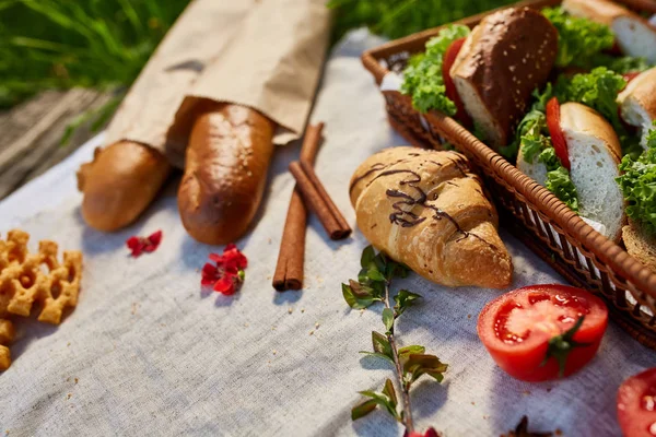 Корзина для пикника с бутербродами, багет и круассан на скатерти, плоский уголок, избирательный фокус — стоковое фото
