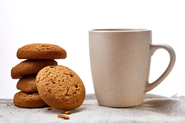 White porcelain mug of tea and sweet cookies on homespun napkin over white background, top view, selective focus — Stock Photo, Image