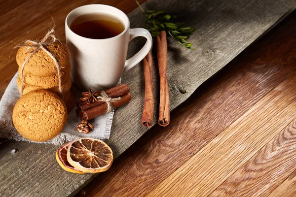 Concepto tradicional de té de Navidad con una taza de té caliente, galletas y decoraciones en una mesa de madera, enfoque selectivo —  Fotos de Stock