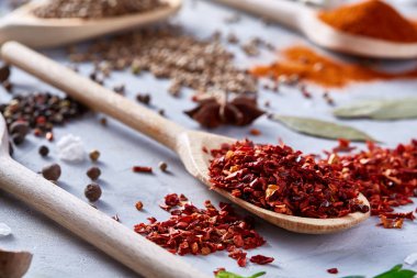 Kırmızı sıcak biber içinde beyaz dokulu arka plan, üstten görünüm, yakın çekim, seçici odak tahta kaşık pul biber.