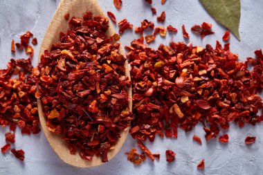 Kırmızı sıcak biber içinde beyaz dokulu arka plan, üstten görünüm, yakın çekim, seçici odak tahta kaşık pul biber.