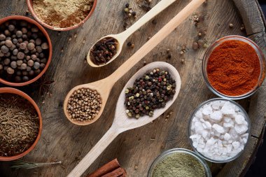 Tahta kaşık ve kase ve biraz tuz bir eski ahşap varil, üstten görünüm, yakın çekim, seçici odak içinde çeşitli baharatlar.