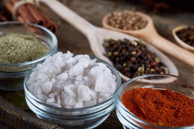 Tahta kaşık ve kase ve biraz tuz bir eski ahşap varil, üstten görünüm, yakın çekim, seçici odak içinde çeşitli baharatlar.