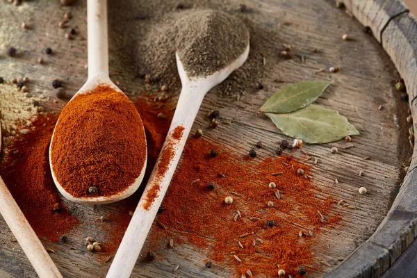 Paprica ve karabiber dolu bir tahta kaşıklar üstten görünüm ahşap varil arka plan, seçici odak üzerinde.